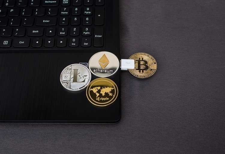 Cryptocurrency Investing: Quick Tips for Beginners A laptop with replica coins of Litecoin, Ripple, ethereum and Bitcoin on it.